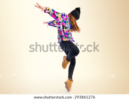 Young woman dancing street dance over ocher background - stock photo