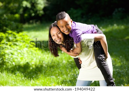 Portrait of a young mother smiling outdoors with happy son  - stock photo