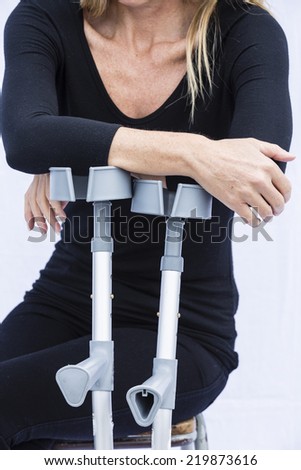 Woman and Crutches/ An injured woman using crutches - stock photo