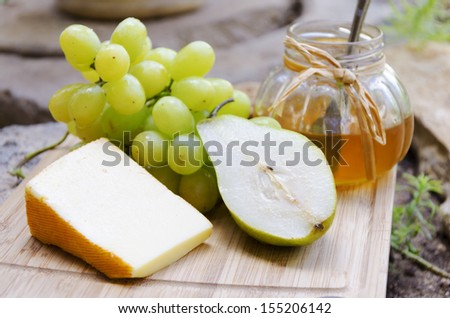  - stock-photo-french-cheese-saint-paulin-with-pear-grape-and-honey-on-the-board-in-the-garden-155206142