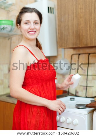 - stock-photo-happy-woman-in-red-cleaning-gas-stove-with-melamine-sponge-in-kitchen-150420602