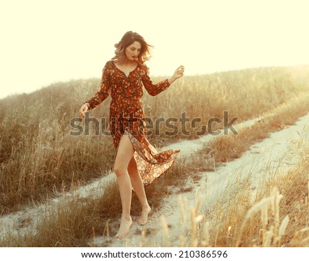 http://thumb9.shutterstock.com/display_pic_with_logo/1258057/210386596/stock-photo-beautiful-fashionable-woman-in-a-dress-in-the-sun-in-the-wind-walks-in-a-field-on-the-way-210386596.jpg