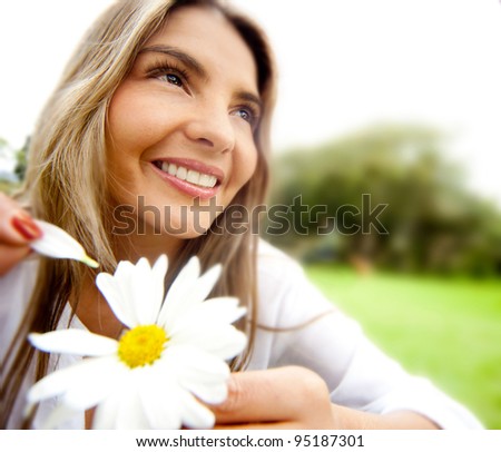 Woman outdoors holding a flower playing he loves me or not - stock photo - stock-photo-woman-outdoors-holding-a-flower-playing-he-loves-me-or-not-95187301