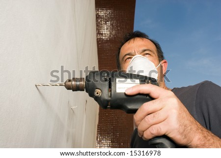 stock-photo-a-man-is-holding-a-power-drill-and-drilling-into-a-wall-he-is-wearing-a-mask-and-looking-away-15316978.jpg