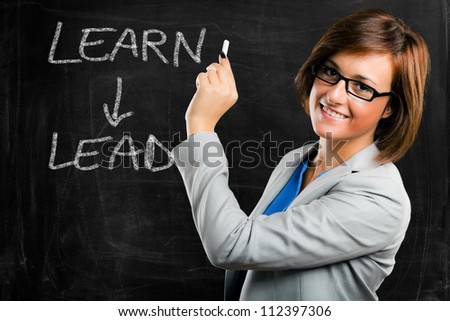 Beautiful woman writing a motivational concept on a blackboard - stock photo