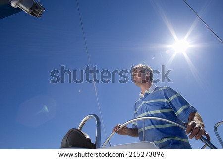  boat out at sea, steering, low angle view (lens flare) - stock photo