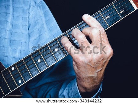 Left hand of musician, guitarist playing chord on acoustic guitar