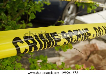 Yellow tape barrier surrounding a crime scene under investigation by the police. - stock photo