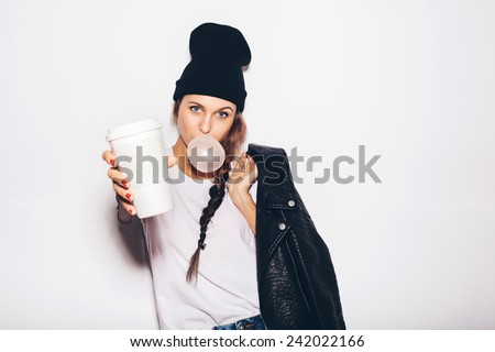 black beanie giving cup of coffee and inflating bubble of chewing gum 