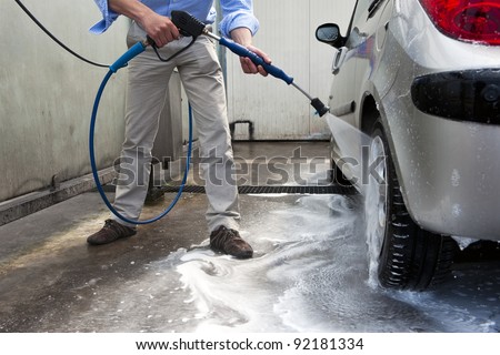 stock-photo-man-wahsing-his-car-in-the-stall-of-a-car-wash-using-a-high-pressure-water-jet-92181334.jpg