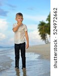 Small photo of Full growth portrait on a tropical beach: handsome slim boy - 8 years old - in wet clothes without shoos ankle-deep in water. He pondered and I put a hand to face.