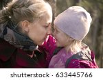 Small photo of A little girl and mother Caucasian (European) appearance look at each other and smile; Mother cares and protects her daughter, gazing at her; They come in contact with noses
