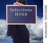 Small photo of A women holding a chalk board with word " INFECTIONS H5N8 " isolated in a background of blue sky. H5N8 is a subtype of the Influenza A virus.