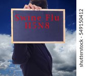 Small photo of A women holding a chalk board with word " SWINE FLU H5N8 " isolated in a background of blue sky. H5N8 is a subtype of the Influenza A virus.