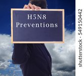 Small photo of A women holding a chalk board with word " H5N8 PREVENTIONS " isolated in a background of blue sky. H5N8 is a subtype of the Influenza A virus.