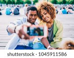 Small photo of Selective focus on young african american friends posing while talking picture on modern smartphone camera sitting with dog in park, dark-skinned couple using mobile for making photo resting together