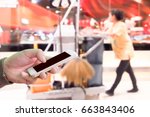 Small photo of Man use mobile phone, blurred image of the cleaning staff in the mall as background.(Building cleaning service is just a phone call away.)