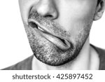 Small photo of male lips with untrimmed beard at closeup.Close up of male part of face. wry mouth