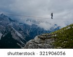 Small photo of MONTE PIANA, DOLOMITES/ITALY - SEPTEMBER 08, 2013: an acrobat on a rope tended above an abyss during "Highline Meeting" of tightrope walkers from around the world taking place every year on september