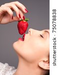 Seductive woman with red lips eating a fresh strawberry - stock photo