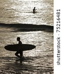 silhouette of two surfers at...