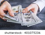 stock-photo-caucasian-hands-counting-dollar-banknotes-on-dark-wooden-surface-401075236.jpg