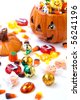 Scatter Halloween candies and orange pumpkin filled by them - stock photo