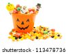Jack-o-lantern candy pail with a pile of colorful Halloween candy - stock photo