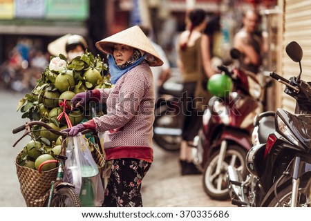 HO CHI MINH, VIETNAM - JAN 15, 2016: the Vietnamese woman sells cocoes on the street in Hochiminh (Saigon) on the sunset. Saigon is the largest city in Vietnam
