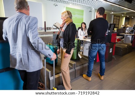 Airline Passengers Weighting Their Luggage At Airport