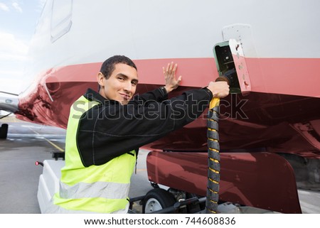 Portrait Of Crew Member Charging Airplane On Runway