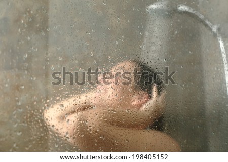 Unfocused portrait of a woman showering through the bath screen with little drops