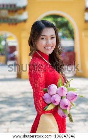 Vertical portrait of an attractive woman in traditional wearing with lotus in hands