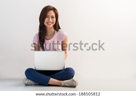 Vietnamese female sitting on the floor and working on the laptop