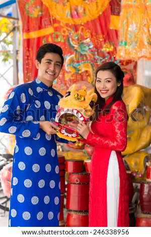Young couple in ao dai dresses holding a mask of lion