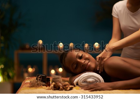 Happy young woman receiving relaxing back massage