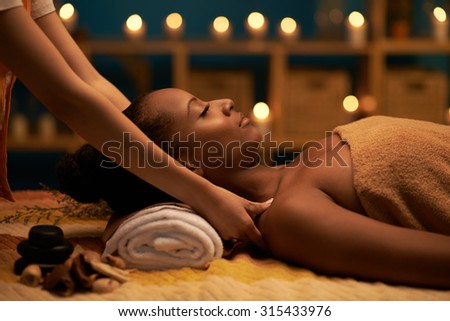 African-American woman receiving relaxing massage in spa salon