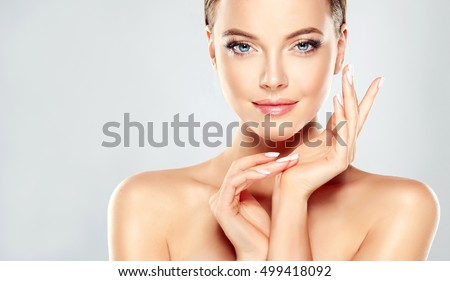 Beautiful Young Woman with Clean Fresh Skin touch own face . Facial treatment . Cosmetology , beauty and spa .
