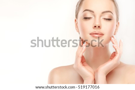 Beautiful Young Woman with Clean Fresh Skin touch own face . Facial treatment . Cosmetology , beauty and spa .