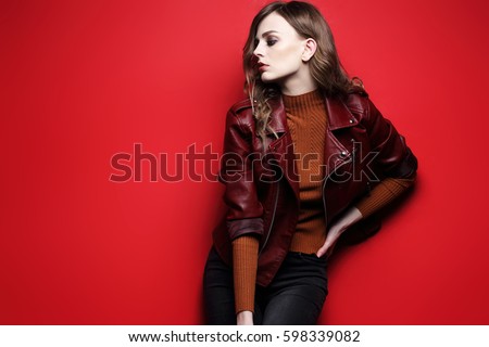 fashion model beautiful young woman. leather jacket, studio shot, red background