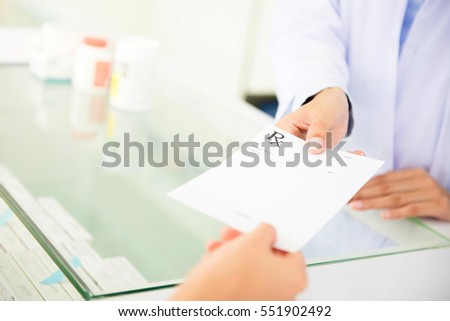 Customer (patient) giving prescription to pharmacist in pharmacy