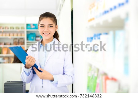 Beautiful smiling Asian female pharmacist working in a pharmacy (or drugstore) with customer friendly attitude
