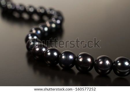 Black pearl necklace on a dark background with reflection