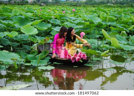 HANOI, VIETNAM, JUNE 12: Unidentified Vietnamese girls wear Ao dai and sit on boat in lake of lotus on June 12, 2010 in Hanoi, Vietnam. Ao dai is famous traditional custume for woman in VIetnam.