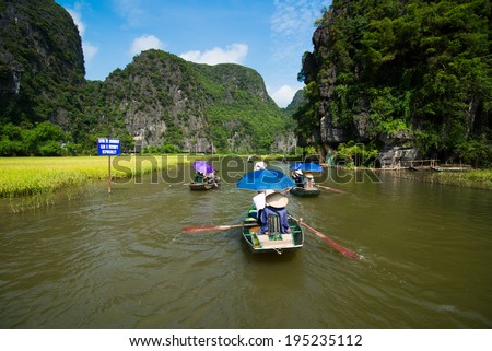 NINH BINH, VIETNAM - MAY 27: Unidentified travellers with rower guides in a boat trip visiting Tam Coc on May, 27, 2014 in Ninh Binh, Vietnam. Tam Coc is the destination of Ninh Binh Province.