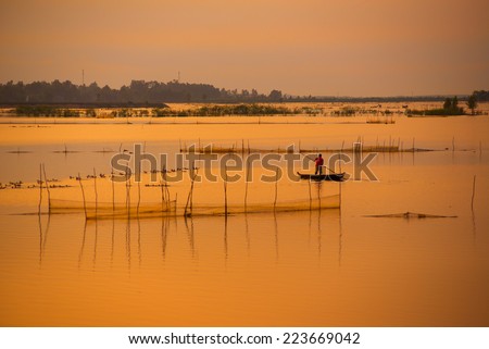 Fisher on boat in water season in sunrise in Dong Thap, Vietnam