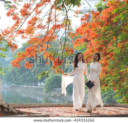 Vietnamese girls wear Ao dai near blooming flamboyant flowers