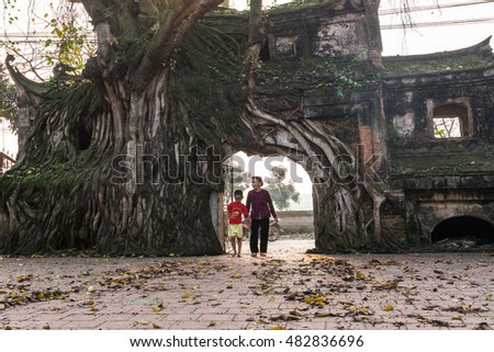 VINHPHUC, VIETNAM, APRIL 10, 2016: A boy with his grandmother go through an ancient gate in a village in Vinh Phuc province, Vietnam. Village gate is a specific of Northern country side in Vietnam.