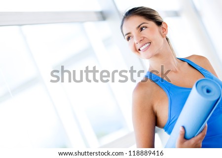 Beautiful woman with a yoga mat at the gym