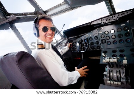 Male pilot sitting in an airplane cabin flying and smiling